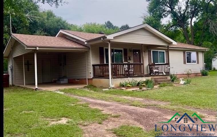 Single story home featuring covered porch, a carport, a front yard, and driveway