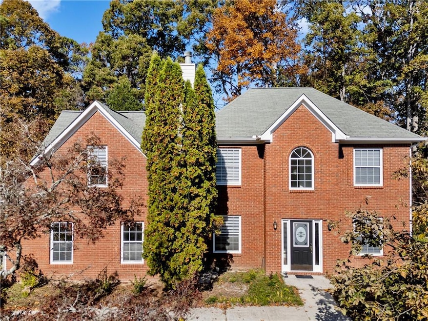 Colonial home featuring a chimney, brick siding, and a shingled roof