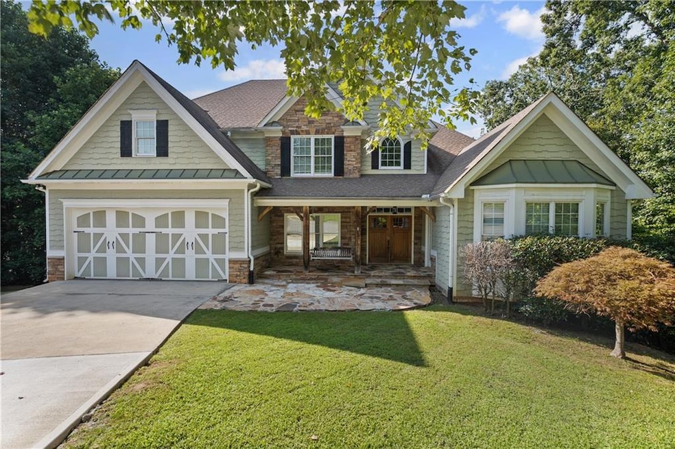Craftsman house featuring a standing seam roof, covered porch, a front yard, and stone siding