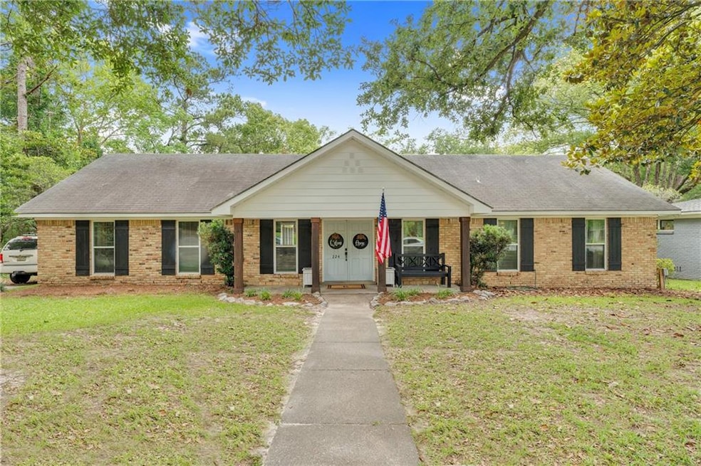 Single story home featuring brick siding, covered porch, and a front yard
