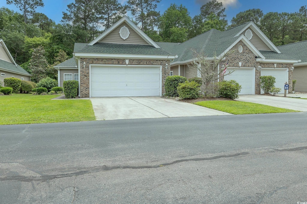 View of front of property with brick siding, concrete driveway, a front yard, and a shingled roof