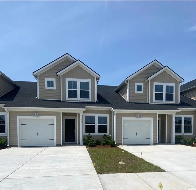 View of front of house featuring concrete driveway and roof with shingles