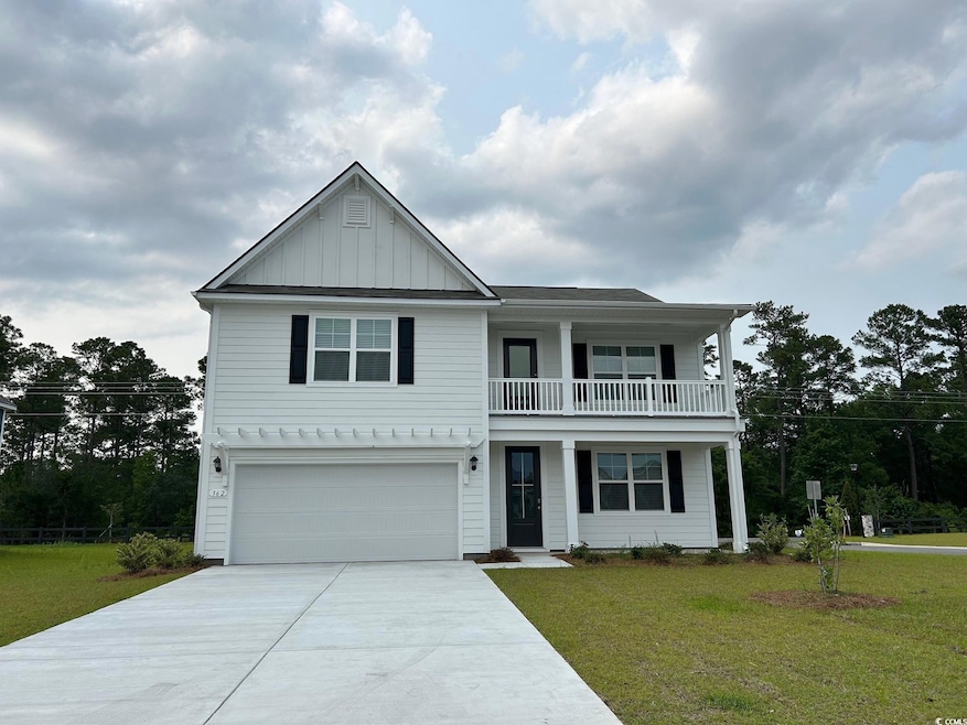 View of front facade with a balcony, concrete driveway, a front yard, and an attached garage