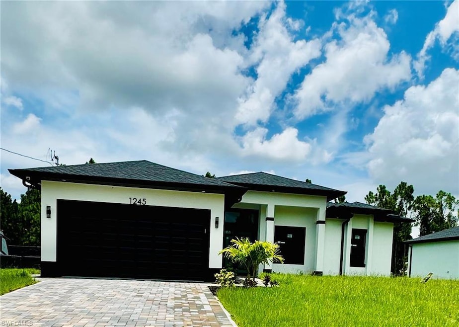Prairie-style home featuring stucco siding, a garage, decorative driveway, and roof with shingles