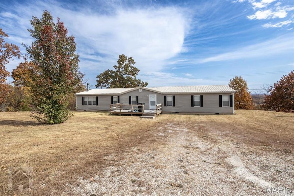 Large mobile home with a new wooden deck and a front lawn. Vinyl siding and metal roof. Poured concrete foundation with crawl space.