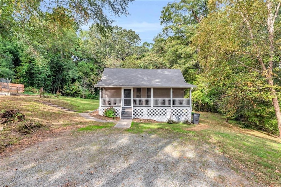 View of front of home featuring a porch, a view of trees, and a front yard