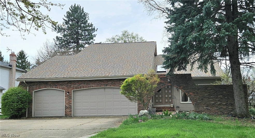 View of front facade with a 3 car garage, turn around driveway, and front entrance brick archway.