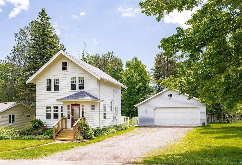 View of front of home featuring an outdoor structure, a front yard, a garage, and a shingled roof