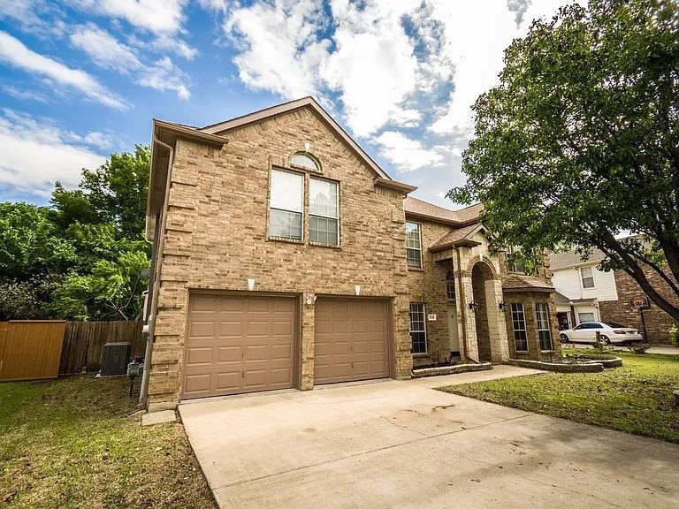 Traditional-style house with an attached garage, driveway, and brick siding