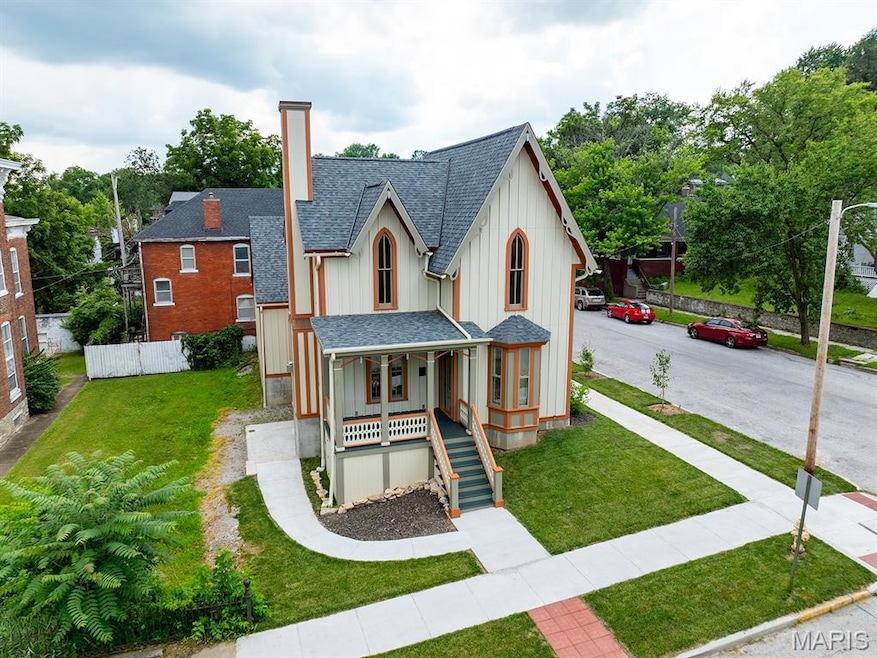 View of front of property with a shingled roof, a porch, board and batten siding, stairway, and a chimney