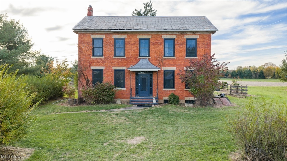 Colonial house with a front lawn, brick siding, and a chimney