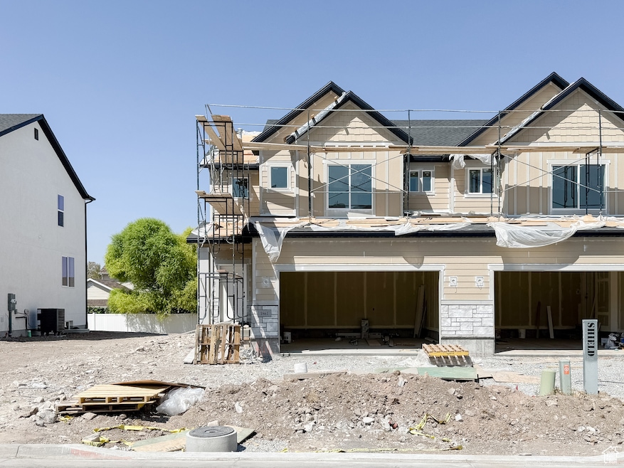 Property under construction featuring an attached garage and stone siding