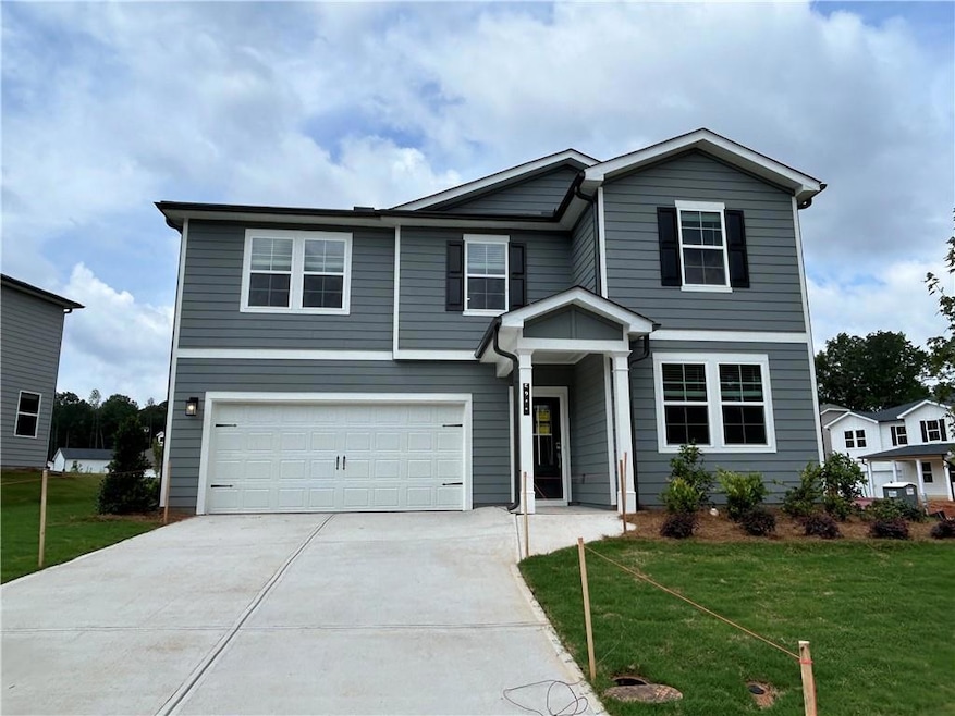 View of front facade with an attached garage, concrete driveway, and a front lawn