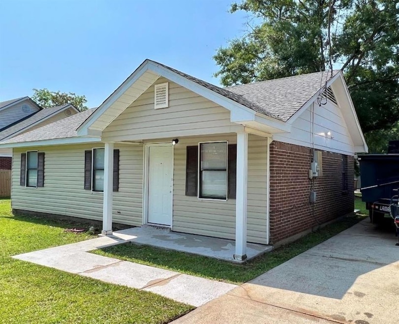 View of front facade with roof with shingles, brick siding, and a front yard