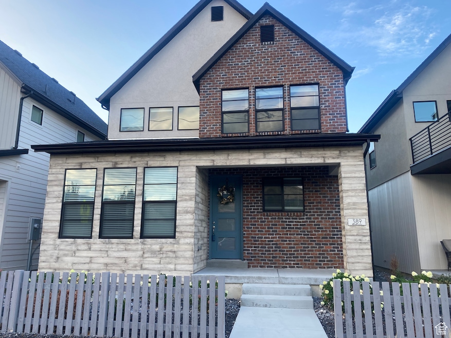 View of front of property featuring brick siding, a fenced front yard, stone siding, and covered porch