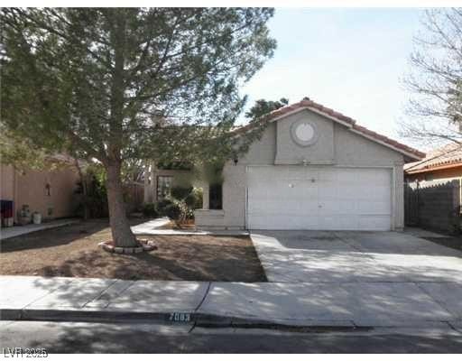 View of front of property featuring an attached garage, driveway, and stucco siding