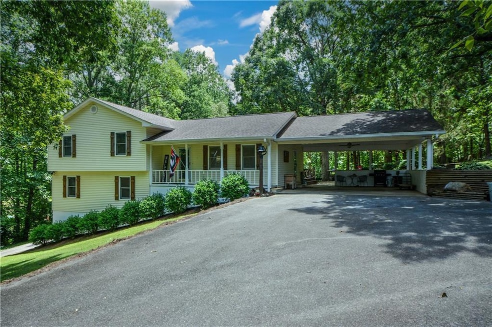 Split level home with asphalt driveway, a carport, covered porch, and roof with shingles