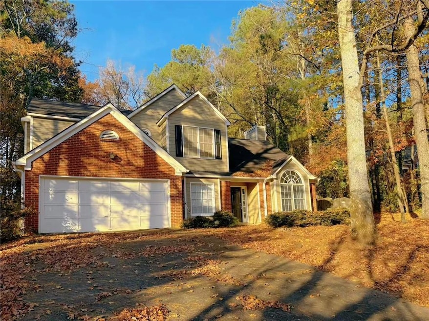 Traditional-style home with brick siding, a chimney, a garage, and driveway