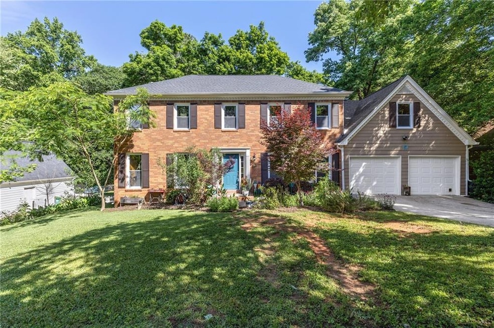 Colonial home with a front yard, driveway, and bri
