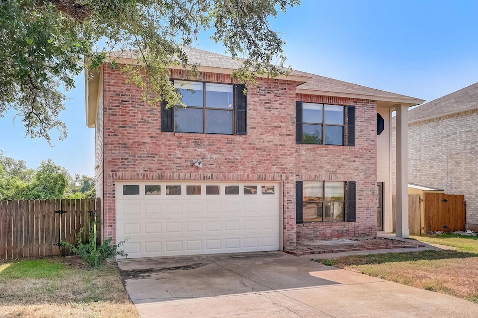 Traditional home featuring a garage, driveway, and brick siding