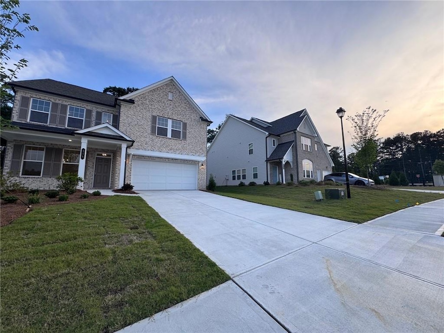 View of front facade featuring an attached garage, concrete driveway, a front yard, and brick siding