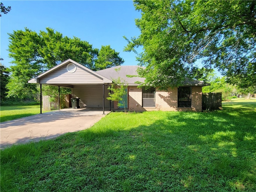 View of front facade with concrete driveway, an attached carport, and brick siding