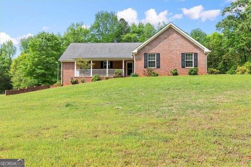 Ranch-style house featuring a porch and a front la