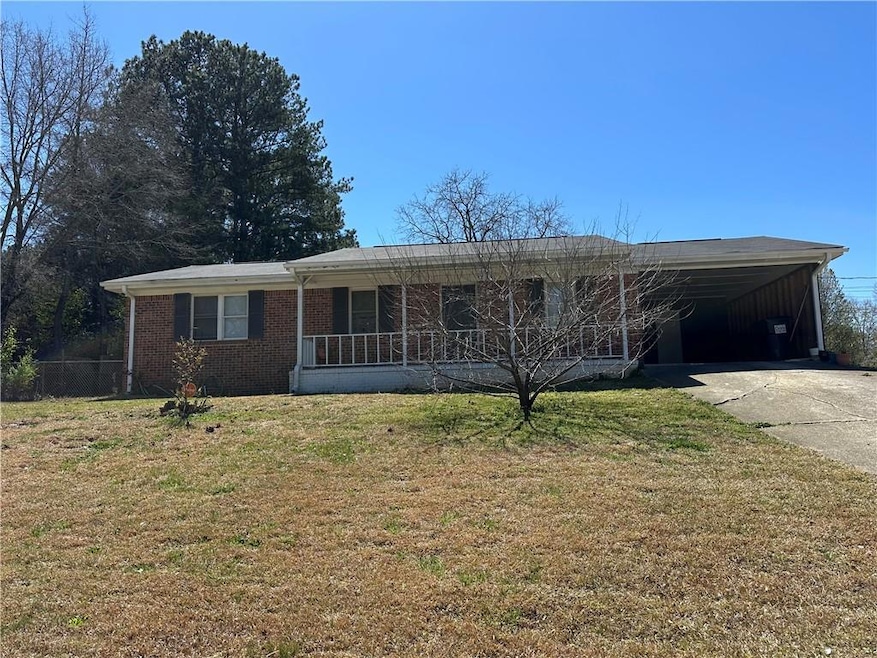 Single story home with a carport, brick siding, concrete driveway, and a front yard