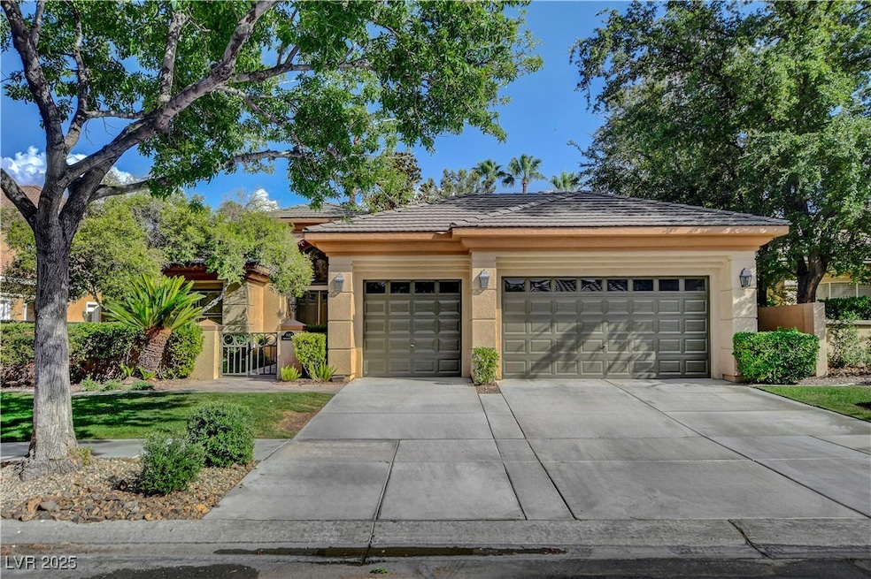 View of front facade featuring driveway, stucco siding, a garage, and a tiled roof