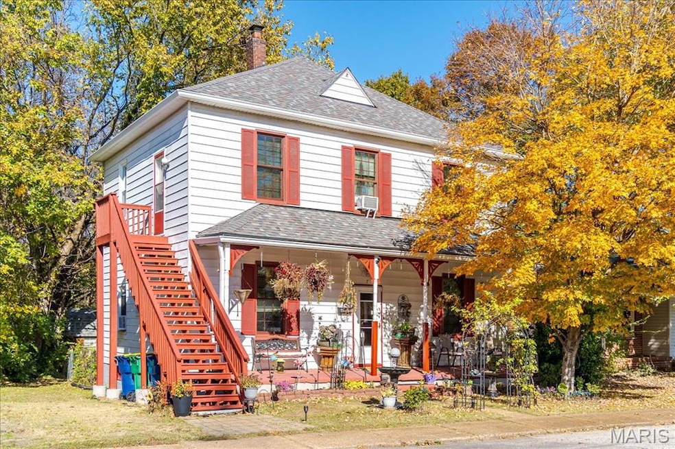 View of front facade featuring a shingled roof, a chimney, and stairs