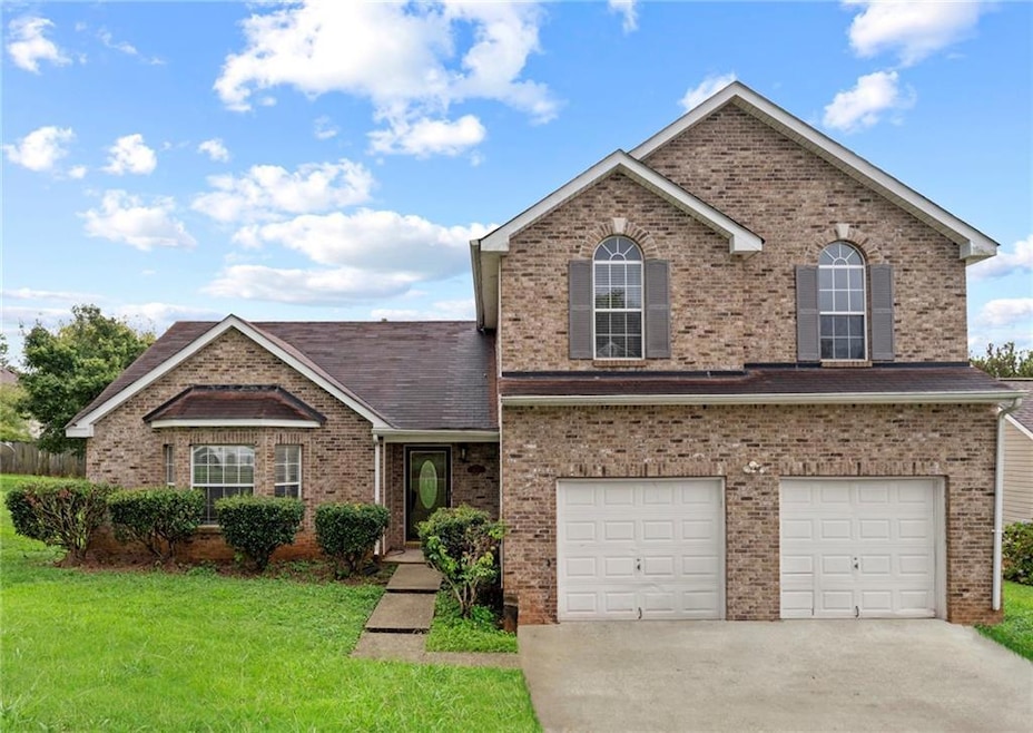 Traditional-style house featuring brick siding, a garage, concrete driveway, a front lawn, and roof with shingles
