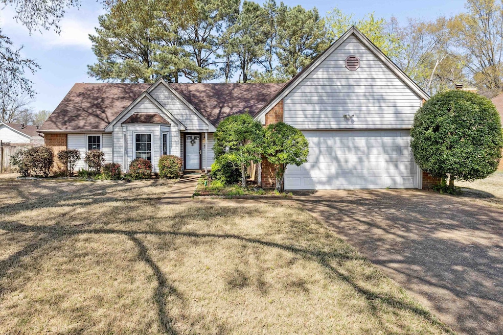 View of front of house featuring brick siding, driveway, an attached garage, and a front lawn