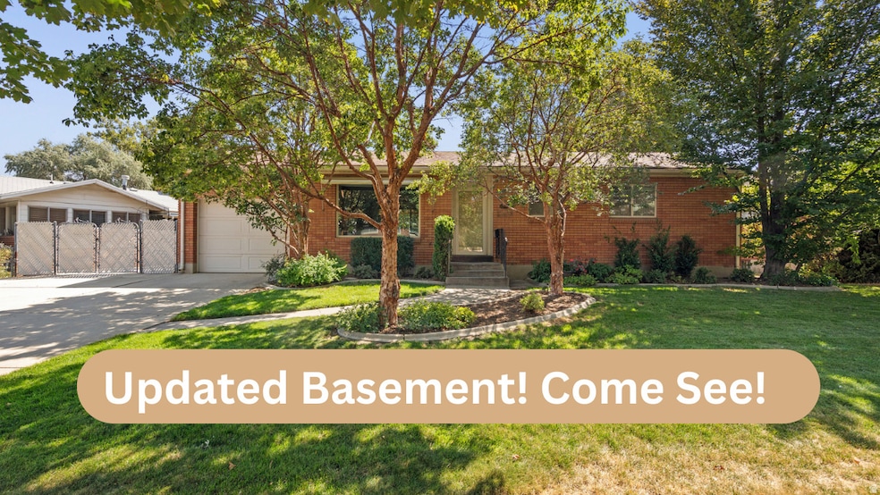 View of front of home featuring brick siding, a front yard, driveway, a gate, and an attached garage