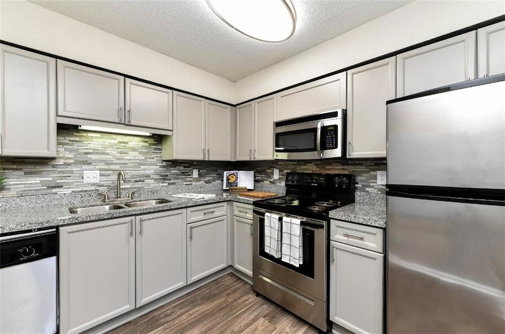 Kitchen with tasteful backsplash, dark hardwood / 