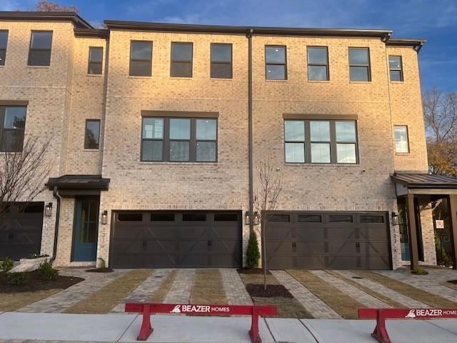 Modern home with decorative driveway, brick siding, and an attached garage