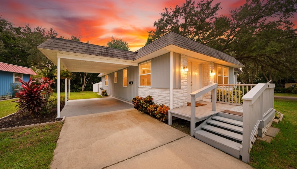 View of front of house with an attached carport, concrete driveway, stone siding, and a front lawn