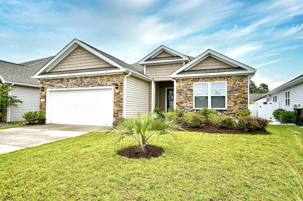 View of front facade featuring stone siding, a garage, a front lawn, and concrete driveway