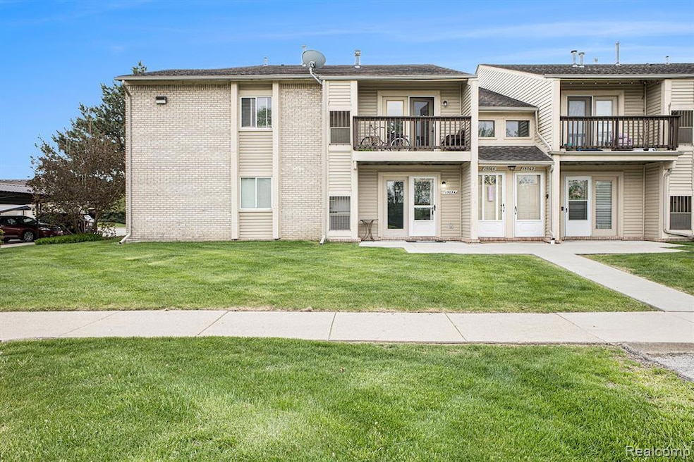 View of front of house featuring a balcony, brick siding, a front lawn, and a shingled roof