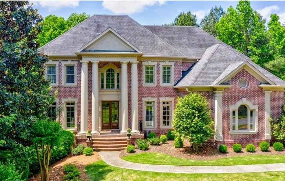 Greek revival house featuring roof with shingles, french doors, and brick siding