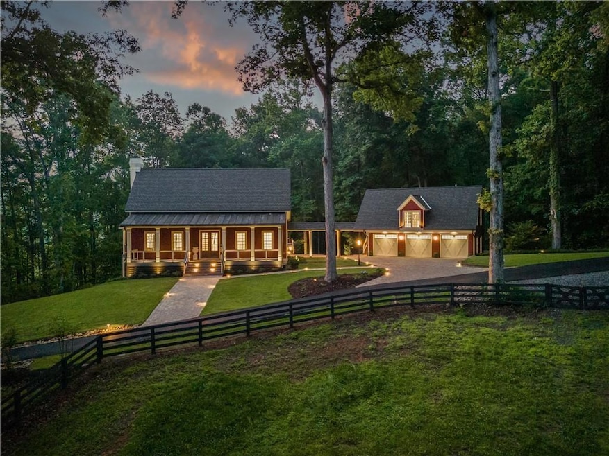 Rear view of house featuring driveway, a fenced front yard, a chimney, a porch, and a garage