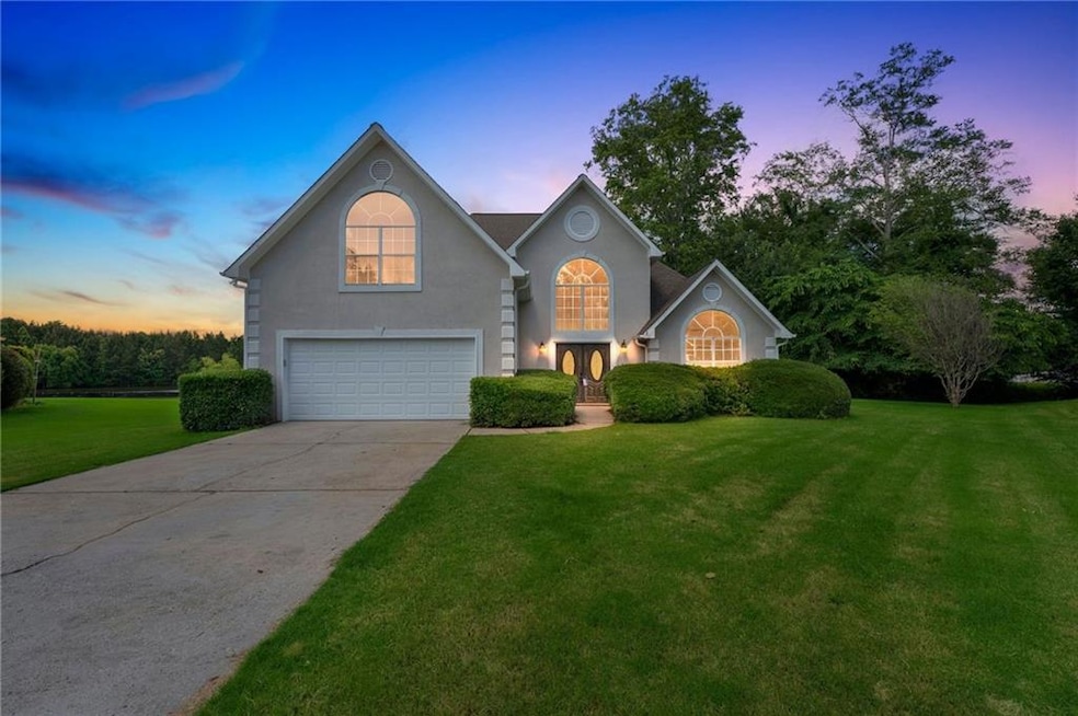 Traditional home featuring an attached garage, a front lawn, driveway, stucco siding, and french doors