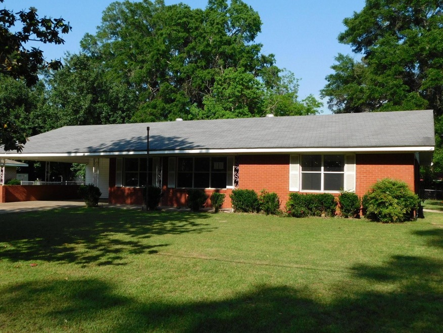 Ranch-style home featuring a carport and a front y
