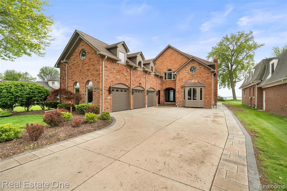 Traditional-style home with brick siding, driveway, a garage, and a front lawn
