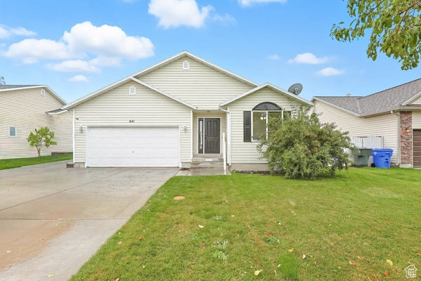 Ranch-style house featuring a front lawn, driveway, and a garage