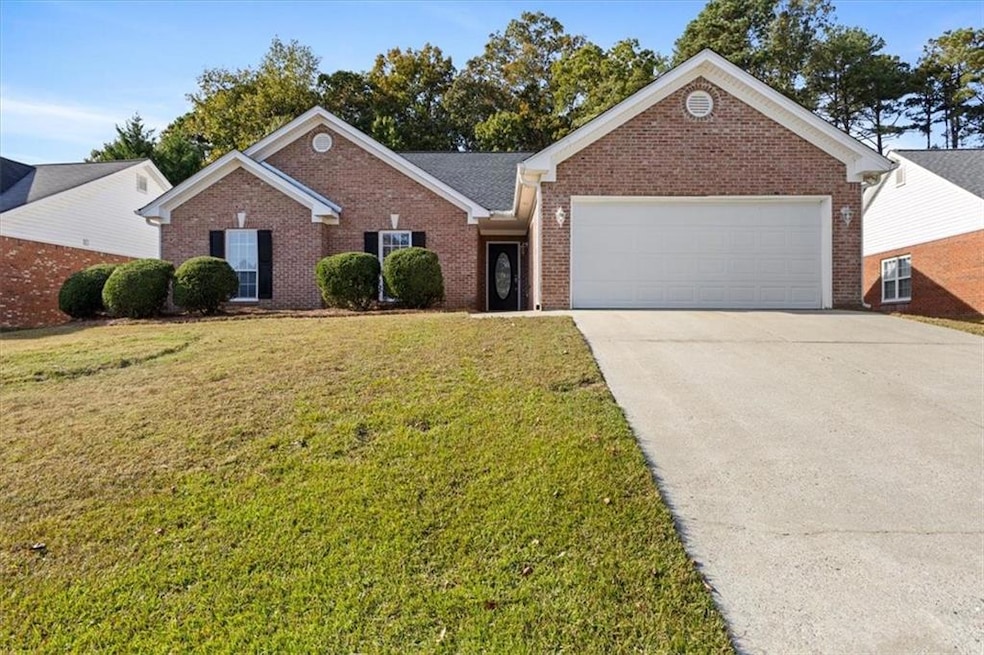 Ranch-style house featuring brick siding, concrete driveway, a front lawn, and a garage
