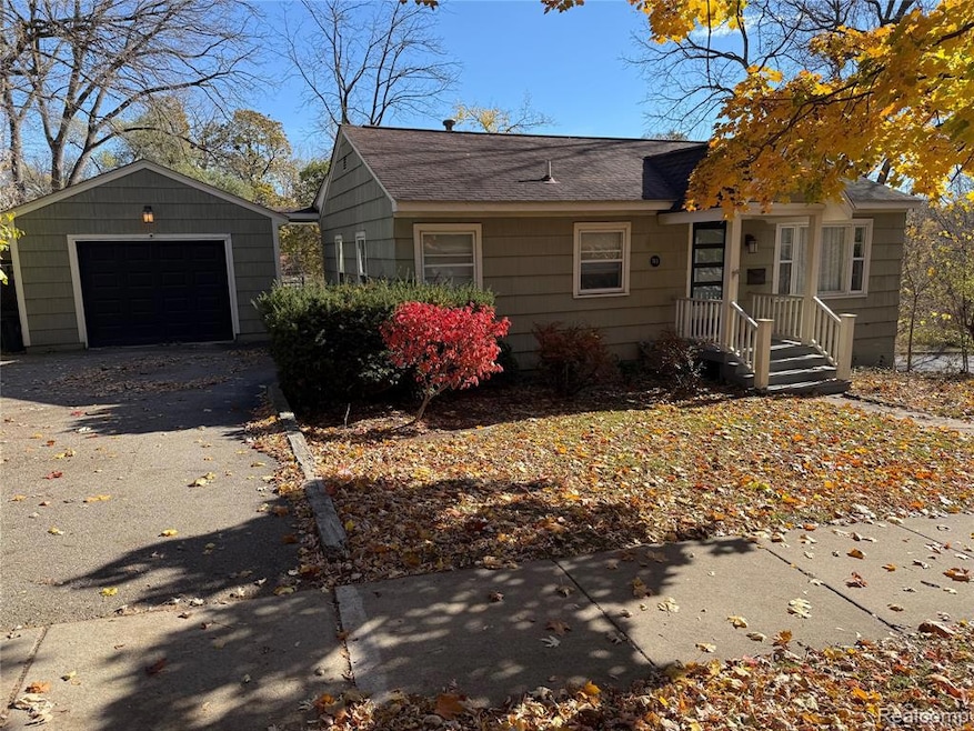 View of front facade with an outdoor structure, a garage, driveway, and a shingled roof