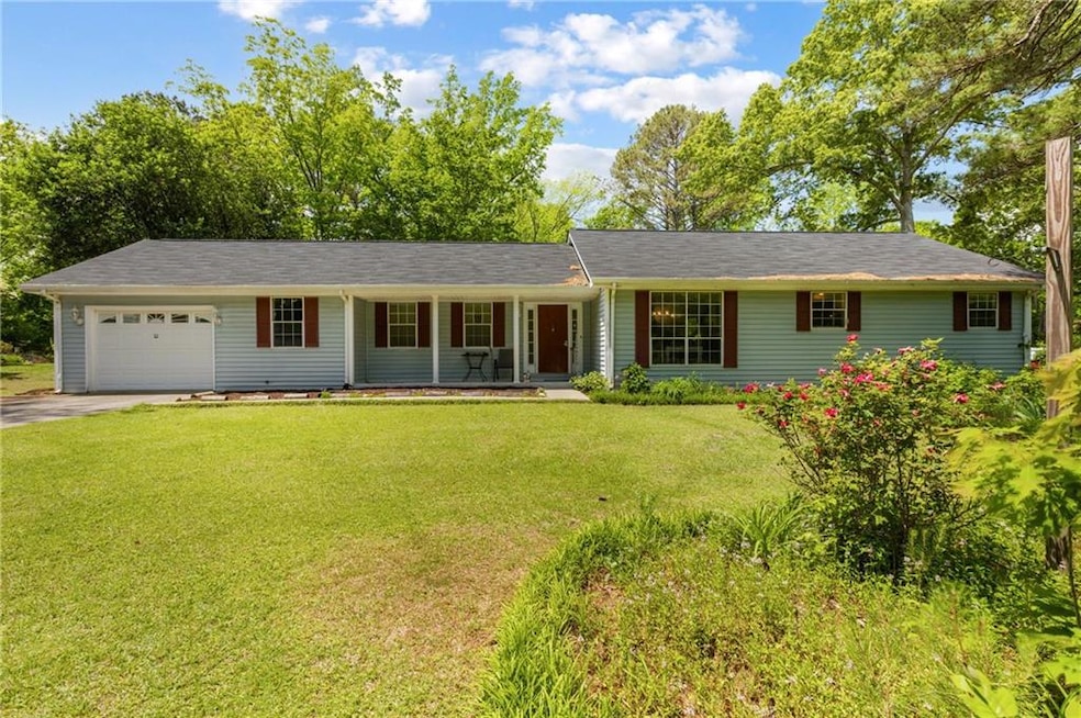Ranch-style home featuring driveway, a porch, a ga