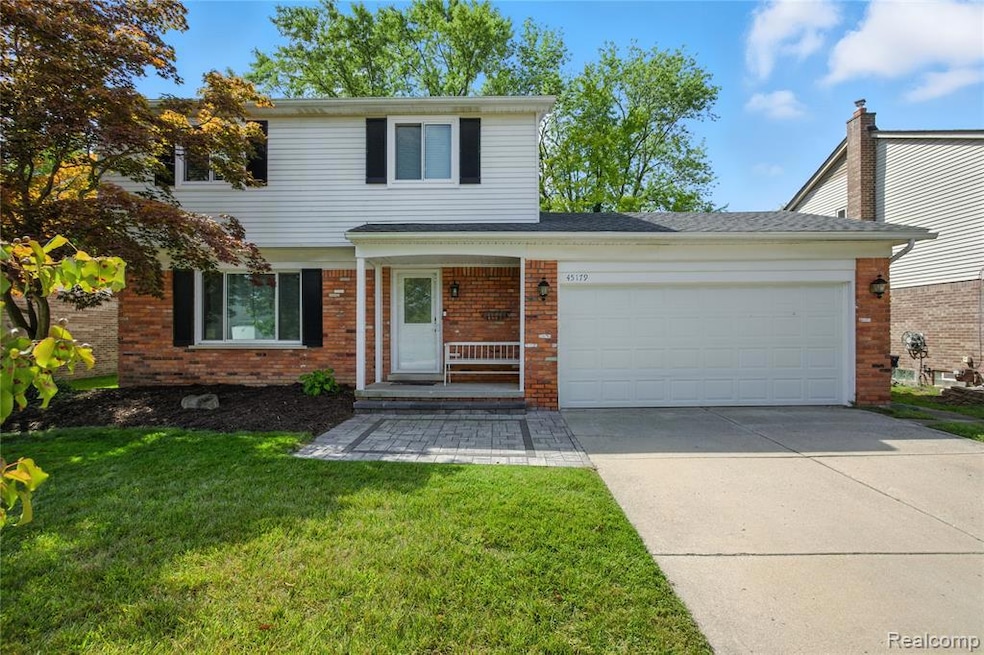 Traditional-style home featuring driveway, an attached garage, a front yard, brick siding, and a porch