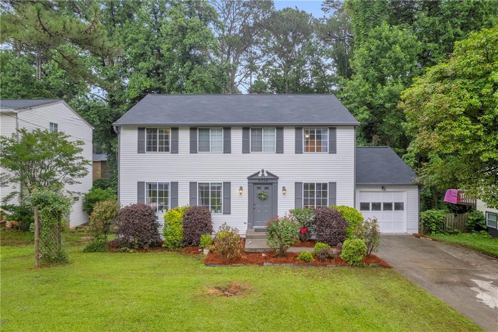 Colonial-style house featuring a garage, concrete driveway, and a front lawn