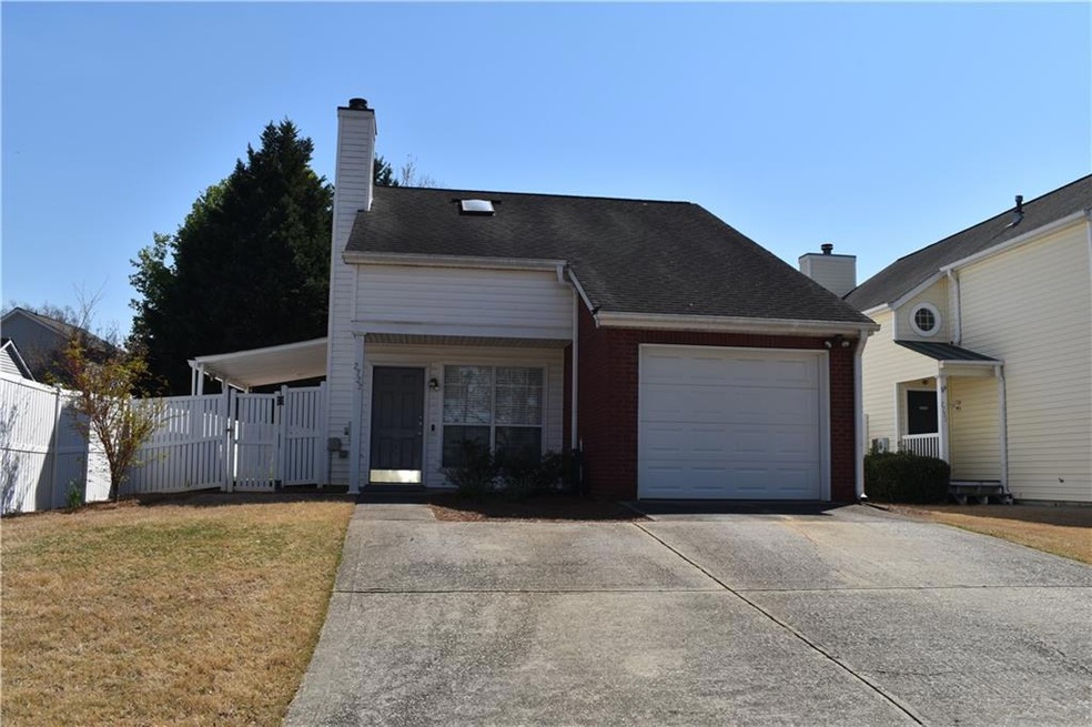View of front facade featuring fence, a chimney, a garage, and driveway